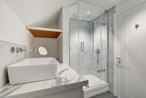 a white bathroom with a sink and a shower at Pen Y Mor in Mawgan Porth