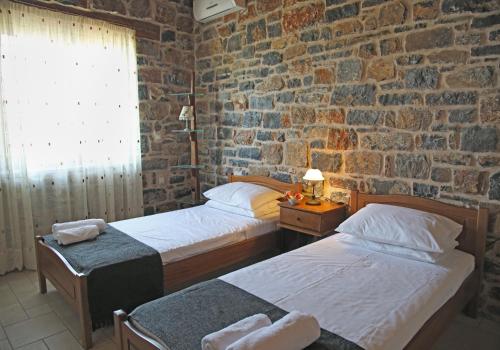 a bedroom with two beds and a brick wall at Kalo Nero Apartments in Makry Gialos