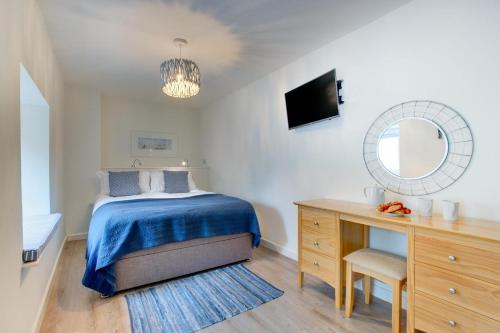 a bedroom with a bed and a dresser and a mirror at Sandpiper in Padstow