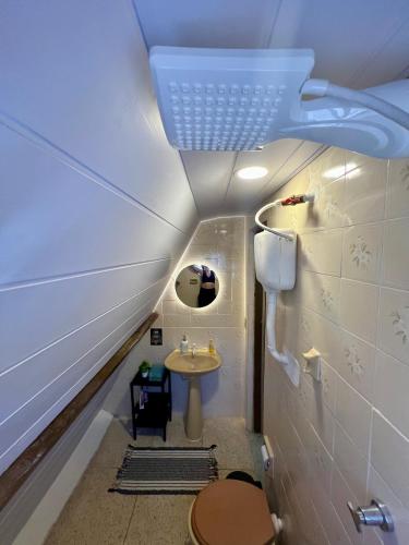 a small bathroom with a toilet and a sink at Casa estilo chale dúplex com 3 quartos, churrasqueira, balanço, chuveirão e a uma quadra da praia in Mangaratiba