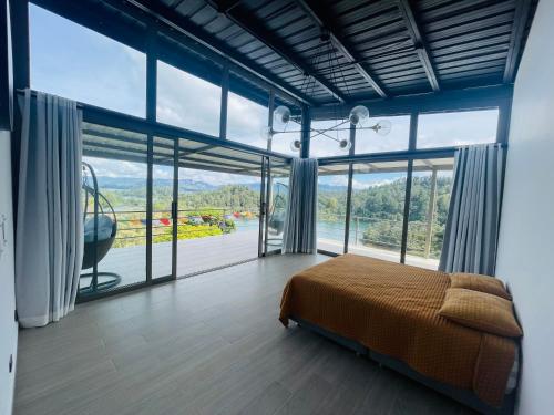 a bedroom with a bed and large glass windows at Casa garuda, hermosa cabaña con vista a la piedra de El Peñol in La Pradera
