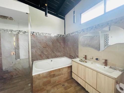 a bathroom with a tub and a sink and a shower at Casa garuda, hermosa cabaña con vista a la piedra de El Peñol in La Pradera