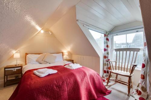 Un dormitorio con una cama roja con una silla y una ventana. en 6 Baileys Lane, en St Ives