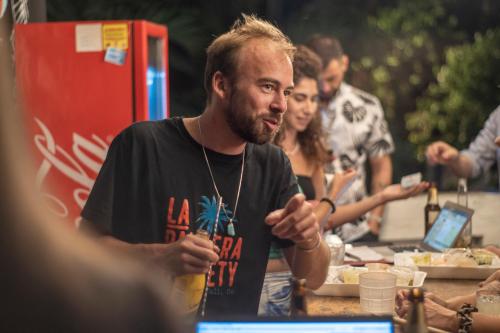 a man sitting at a table talking to people at La Palmera Hostel in Cali