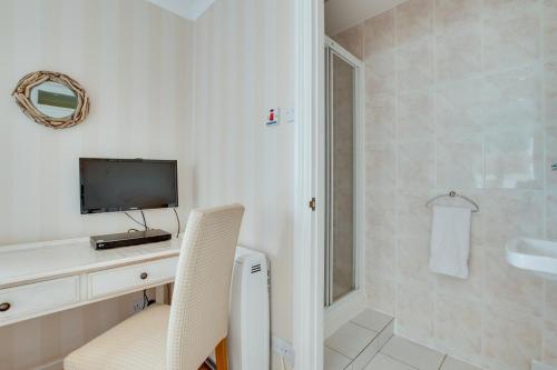 baño con escritorio, TV y ducha en Flat 20 Clifton Court, en Croyde