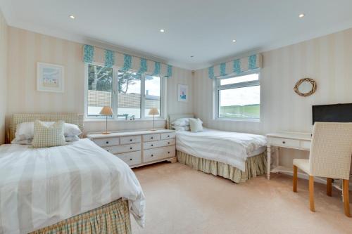 Un dormitorio con dos camas y un escritorio y ventana. en Flat 20 Clifton Court, en Croyde
