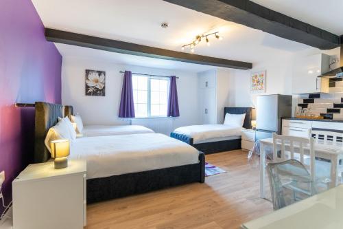 MackworthにあるMundy Arms Roomsのベッド2台とテーブル、キッチンのある寝室