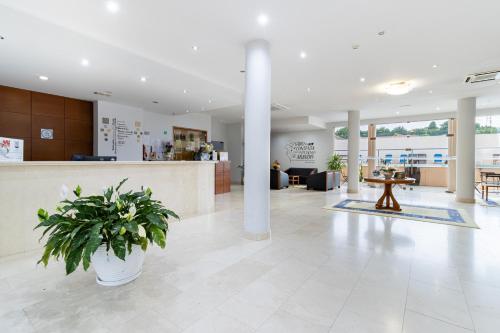 a lobby with a plant in the middle of a building at Hotel La Fontaine in Esmoriz