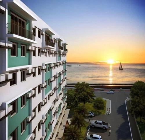 a building with a view of the ocean at sunset at DaLei 2-330 Sleeps 8pax at Marina Spatial Condominium in Dumaguete City in Dumaguete