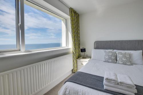 Praa SandsSeacroft Barton的一间卧室，里面有一张床和一扇大窗户。