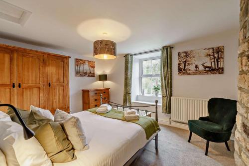 a bedroom with a bed and a chair and a window at High Green Cottage in Low Eskcleth