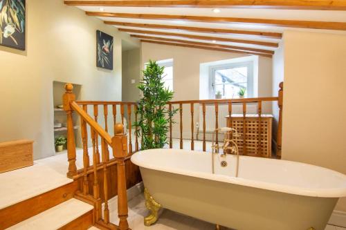 a bath tub in a room with a staircase at High Green Cottage in Low Eskcleth