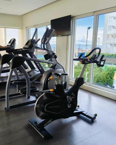 a gym with several cardio machines in a room with windows at DaLei 3-103 Sleeps 6pax at Marina Spatial Condominium in Dumaguete City in Dumaguete