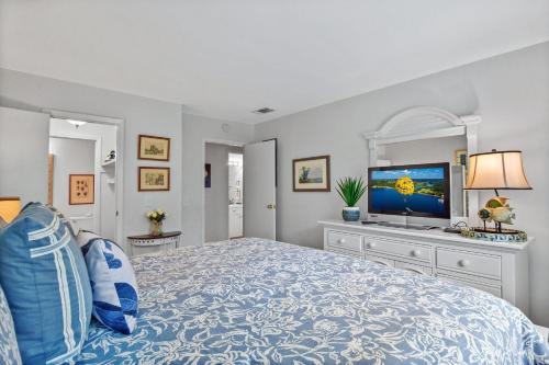Un dormitorio con una cama y un televisor de pantalla plana. en Ocean Walk E-5, en Saint Simons Island