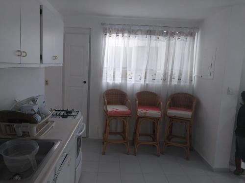 a kitchen with three bar stools in front of a window at Tropical Optimal Tropicana Sur in Sosúa