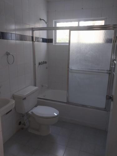 a white bathroom with a toilet and a shower at Tropical Optimal Tropicana Sur in Sosúa