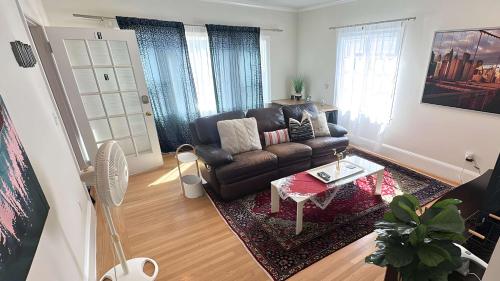 オークランドにあるOak Manor - Chic & Stylish 2BR Apartment Retreatの革張りのソファとテーブルのあるリビングルーム