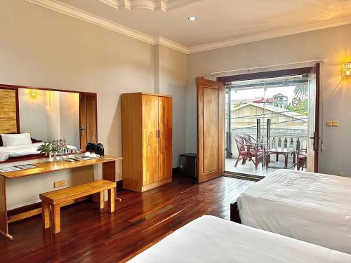 a bedroom with a bed and a desk and a balcony at Youth's Dream Fulfillment Association in Siem Reap