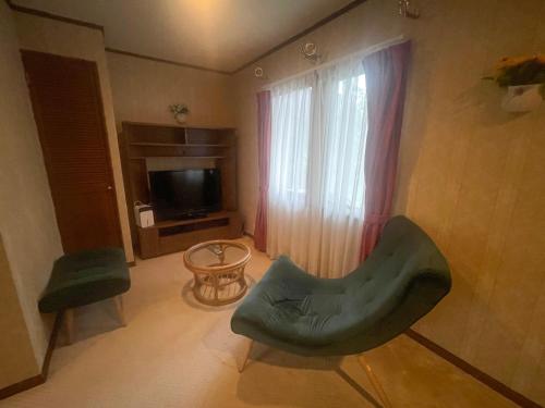 a living room with a green chair and a television at Pension Balmy in Nasu