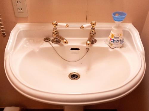 a white sink with a bottle of detergent in it at Pension Balmy in Nasu