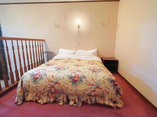 a bedroom with a bed with a floral bedspread at Pension Balmy in Nasu