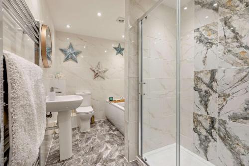 Un baño con ducha, lavabo e inodoro. en Scarlettrose, en Great Torrington