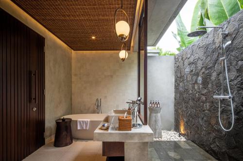 un baño con lavabo y bañera en The Garcia Ubud Villa, en Ubud