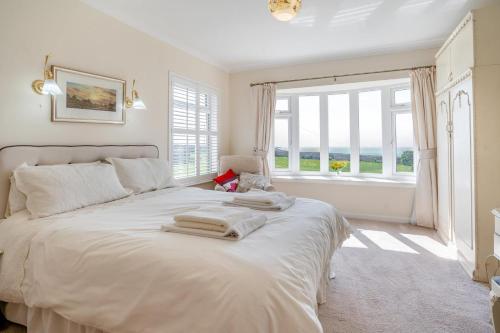 a bedroom with a large white bed with a window at Heavenly View in Southerndown