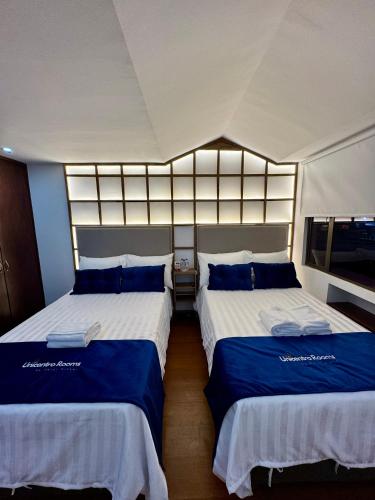 a bedroom with two beds with blue and white sheets at Unicentro Rooms Inn by Saint Michel in Bogotá