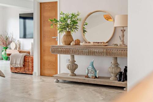 a room with a mirror and a table with vases at Sandpipers - Downderry in Downderry