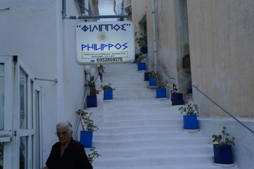 a man walking down a stairway with blue potted plants at Filippos in Agios Kirykos