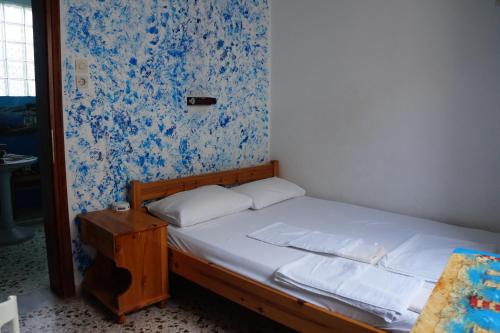 uma pequena cama num quarto com papel de parede azul e branco em Filippos em Agios Kirykos