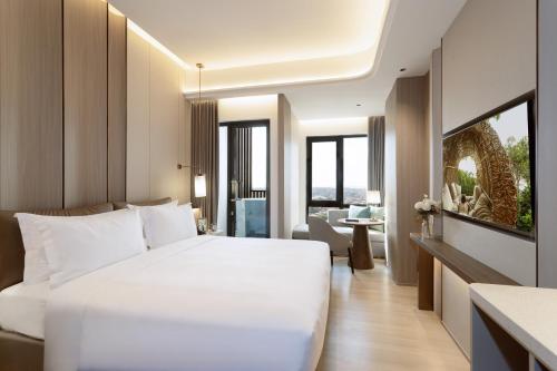 a bedroom with a white bed and a living room at Somerset Queen City Semarang in Stasiun Tawang