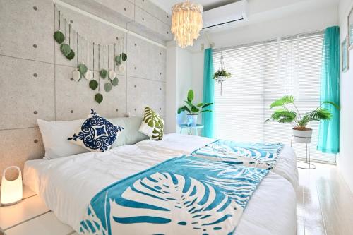 a bedroom with a large bed with blue and white sheets at アロハベース in Takamatsu