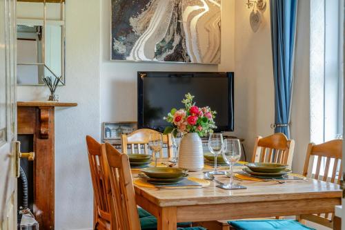 a dining room table with a vase of flowers at Pengwern in Llangranog