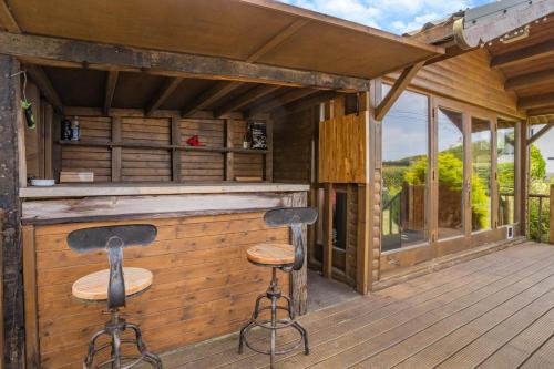 a bar on the deck of a cabin with two stools at Pengwern in Llangranog