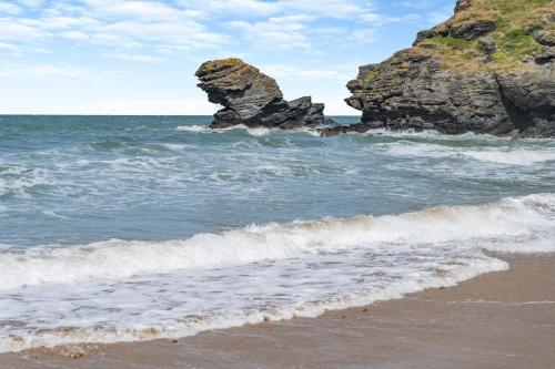a beach with rocks in the ocean with waves at Pengwern in Llangranog