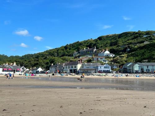 a group of people on a beach with houses at Pengwern in Llangranog