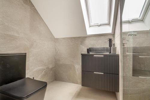 a bathroom with a black toilet and a sink at Siop Penrallt- Rhiw in Bottwnog