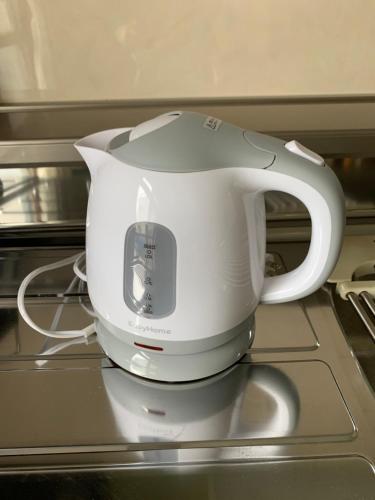 a white tea kettle sitting on top of a stove at NU1 Guesthouse NUI okhotsk女満別 in Abashiri