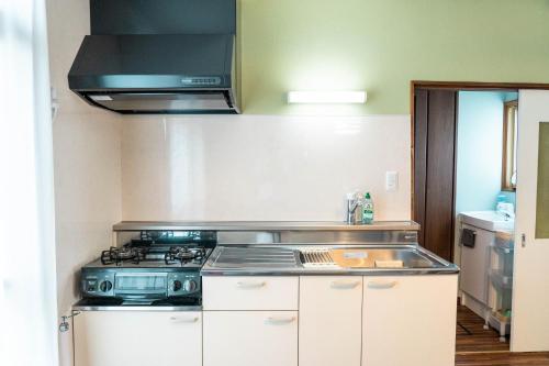 a kitchen with a stove and a microwave at NU1 Guesthouse NUI okhotsk女満別 in Abashiri