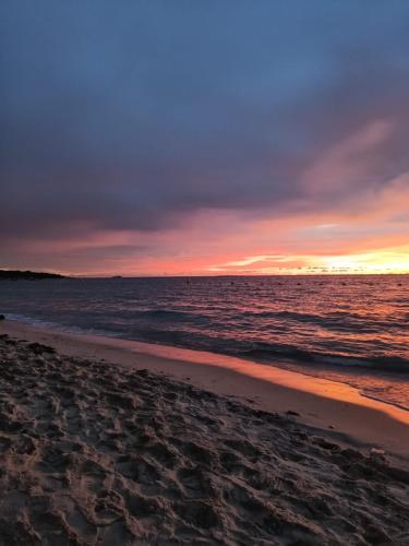 a sunset on a beach with the ocean at Cabañas Palos Locos in Baru