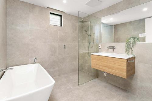 a bathroom with a tub and a sink and a shower at Shellharbour Seaview Luxury Escape in Shellharbour