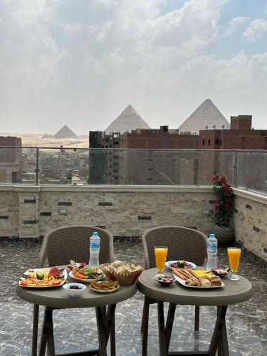 two tables with food and drinks on a balcony with pyramids at king pyramids in Cairo