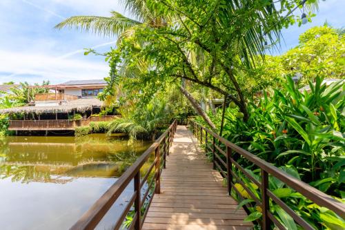 a wooden bridge over a river with a house in the background at Hoi An Eco Lodge & Spa in Hoi An