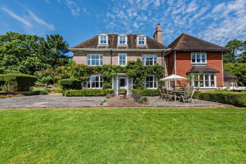 a large brick house with a lawn in front of it at Denswood House in Brightling