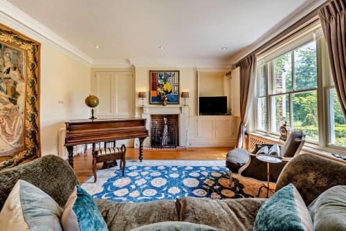 a living room with a couch and a piano at Denswood House in Brightling