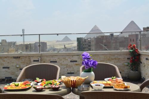 a table with plates of food on a balcony with pyramids at king pyramids in Cairo