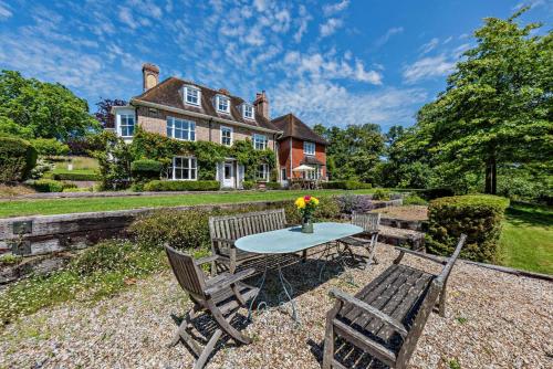 a table and chairs in front of a house at Denswood House in Brightling