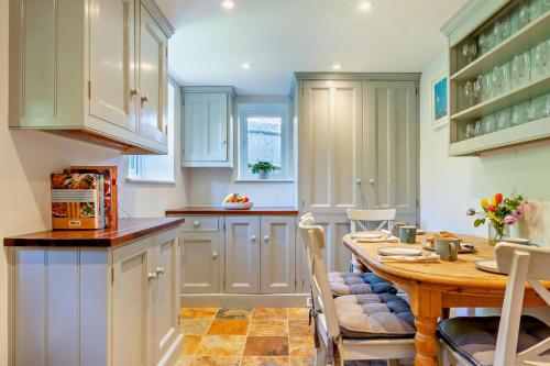 a kitchen with a table and chairs and a kitchen with white cabinets at The Granary - Ticehurst in Ticehurst